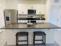 Bright kitchen boasts stainless steel appliances, white cabinets, and a granite island with seating at 3974 Mekong Ct, St Cloud, FL 34772
