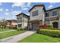 Exterior view of a townhome with manicured lawn, features a tile roof, and a two-car garage at 5935 Tivoli Gardens Blvd, Orlando, FL 32829