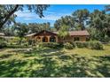 Charming single-story house featuring an arched entry and lush front yard shaded by mature trees at 1625 Itchepackesassa Dr, Lakeland, FL 33810