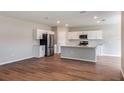 Open kitchen with white cabinets, stainless steel appliances, an island, and hardwood flooring at 729 Ambleside Dr, Haines City, FL 33844