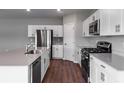 Modern kitchen featuring white cabinets, stainless steel appliances, an island with a sink, and hardwood flooring at 729 Ambleside Dr, Haines City, FL 33844