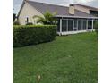 A green backyard with a screened lanai is enhanced by a manicured hedge at 2202 Garden Lake Dr, Winter Haven, FL 33884