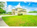 A view of the side of the two-story home with a three-car garage, surrounded by a lush green lawn at 383 Blue Lake Cir, Kissimmee, FL 34758