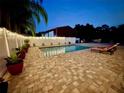 Stunning pool area featuring brick pavers, a privacy fence, string lights, and comfortable lounge chairs at 1423 Spruce N Rd, Lakeland, FL 33809