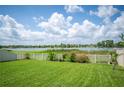 Expansive backyard with lush green grass, a view of a lake, and a white picket fence at 2283 Geneva Dr, Lakeland, FL 33805