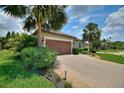 Charming paver driveway, lush greenery, and mature palm trees leading to the home's entrance and two-car garage at 224 Granada Ln, Davenport, FL 33837