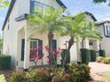 Beautiful home with a charming entryway and lush landscaping featuring colorful flowers and palm trees at 10303 Park Commons Dr, Orlando, FL 32832