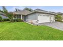 Charming home featuring a well-manicured lawn, a gray exterior, and a convenient two-car garage at 7991 Lake James Blvd, Lakeland, FL 33810