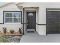 Close-up showcasing the front door, window, and garage door with dark trim at 9413 5Th Ave, Orlando, FL 32824