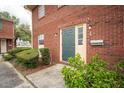 Close-up of brick townhouse entrance with a teal front door and green bushes at 1920 E Edgewood Dr # E1, Lakeland, FL 33803