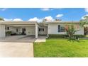The front exterior features lush green grass, a covered carport, and beautiful flowering bushes at 3582 Milano Ave, Lakeland, FL 33803