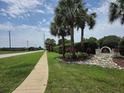 Landscaped community entrance featuring lush greenery, palm trees, and a decorative sign at 4471 Marsh Harbor Dr, Tavares, FL 32778
