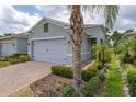 Charming home with a brick driveway, a two-car garage, and lush tropical landscaping at 1890 Flora Pass Pl, Kissimmee, FL 34747