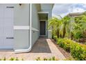 Inviting covered entryway featuring brick pavers surrounded by verdant, tropical landscaping at 1890 Flora Pass Pl, Kissimmee, FL 34747