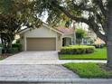 Charming home featuring a brick paver driveway leading to a two-car garage, set amidst lush landscaping at 12064 Navale Ln, Orlando, FL 32827
