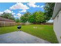 Spacious backyard featuring a well-maintained lawn, partial fencing, fire pit and a barbeque grill at 3826 Sleepy Hill Oaks Loop, Lakeland, FL 33810