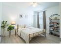 Bright bedroom with a metal-framed bed, neutral bedding, stylish decor, and ample natural light filtering through the window at 573 Vista Villages Blvd, Davenport, FL 33896