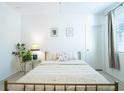 Bright bedroom with a metal-framed bed, neutral bedding, stylish decor, and ample natural light filtering through the window at 573 Vista Villages Blvd, Davenport, FL 33896