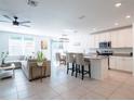 Open-concept living area with kitchen island, dining table, comfortable sofa, and ample natural light, perfect for modern living at 573 Vista Villages Blvd, Davenport, FL 33896
