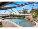 Screened-in pool with rock waterfall feature, spa, and surrounding patio area at 6143 Black Walnut Dr, Bartow, FL 33830