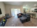 Living room features a comfortable gray sectional couch, stylish chair, sliding glass door, and an open view into the kitchen at 1368 Axel Cir, Winter Haven, FL 33880
