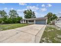 Wide concrete driveway leading up to a charming one-story house featuring a two-car garage with matching light blue doors at 229 Temple Ave, Fern Park, FL 32730