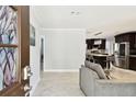 Open-concept living space with tile flooring, a gray sofa, and a view into a modern kitchen with stainless steel appliances at 229 Temple Ave, Fern Park, FL 32730