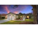 Lovely single-story home with lush landscaping, showcasing curb appeal under a stunning evening sky at 647 San Pedro Dr, Lady Lake, FL 32159
