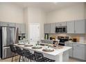 Modern kitchen features stainless steel appliances, gray cabinetry, island with seating, and stylish countertops at 1017 Foreshore Ln, Haines City, FL 33844