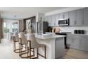Modern kitchen with gray cabinets, stainless steel appliances and a white quartz island with bar seating at 1233 Tidal St, Haines City, FL 33844