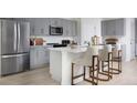 Modern kitchen featuring gray cabinets, stainless steel appliances, and a white quartz island with bar seating at 1233 Tidal St, Haines City, FL 33844