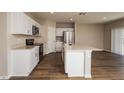 Open kitchen features white cabinets, stainless appliances, and a center island with wood flooring at 4106 Gerbera Daisy Ave, Lake Hamilton, FL 33851