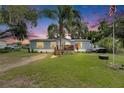 Charming single-story home with light blue siding, a cozy front porch, and a well-maintained lawn at dusk at 4854 Myrtle View N Dr, Mulberry, FL 33860