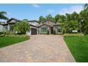 Elegant home exterior with a brick driveway, lush landscaping, and a stone facade, complemented by an attached two-car garage at 2242 Soaring Eagle Pl, Lake Mary, FL 32746