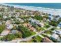 Aerial view of a residential neighborhood near a beach with the subject property indicated by a red arrow at 64 Alberta Ave, Ponce Inlet, FL 32127