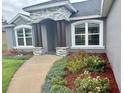 Close up of the home entrance featuring stone detail, an arched entryway, and beautiful landscaping at 7144 Remington Oaks Loop, Lakeland, FL 33810