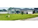 Well-maintained home featuring gray paint, an attached garage, and a lush green lawn at 7144 Remington Oaks Loop, Lakeland, FL 33810