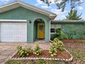 Inviting front entrance with a bright yellow door, complemented by lush landscaping and textured stucco at 1238 Honeytree E Ln, Lakeland, FL 33801