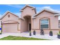 Inviting entrance of a beige home enhanced with white rock landscaping and potted plants at 547 Sardinia Cir, Davenport, FL 33837