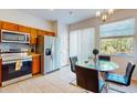Modern kitchen with stainless steel appliances, tile flooring, and a glass dining table near a bright window at 5494 Paradise Cay Cir, Kissimmee, FL 34746