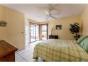 Bright main bedroom featuring tile floors, a ceiling fan, and access to a screened patio at 62 Lakepointe Cir, Kissimmee, FL 34743