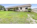 Tan home on a large lot with an extensive, green front yard and garden beds at 124 Pangola Dr, Winter Haven, FL 33880