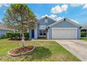 Single-story home featuring a tidy lawn, two car garage, and inviting blue front door at 2576 Boots Rd, Lakeland, FL 33810