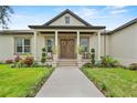 Inviting front porch with decorative columns, double doors, and beautifully landscaped walkway at 9419 Alturas Babson Park Cutoff Rd, Bartow, FL 33830