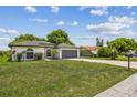 Charming single-story home featuring a gray garage door, arched windows, and a well-maintained lawn at 1003 Edmund Ave, Dundee, FL 33838