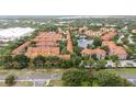 Aerial view of community featuring many units, a pond, pool, and surrounded by mature trees at 6133 Metrowest Blvd # 105, Orlando, FL 32835
