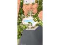Aerial shot of community pool with decorative palm trees, patio furniture, and a nearby pond at 6133 Metrowest Blvd # 105, Orlando, FL 32835