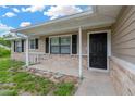 View of a covered front porch with black door, brick accents, and stone pathway at 562 Nardello Dr, Deltona, FL 32725
