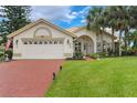 Charming single-story home with a two-car garage, brick driveway, and lush green lawn at 414 Long Cove Ct, Ormond Beach, FL 32174
