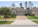 Well-maintained one-story home with brick driveway, stone accents, and a two-car garage at 1553 Amber Leaf Cir, Ocoee, FL 34761